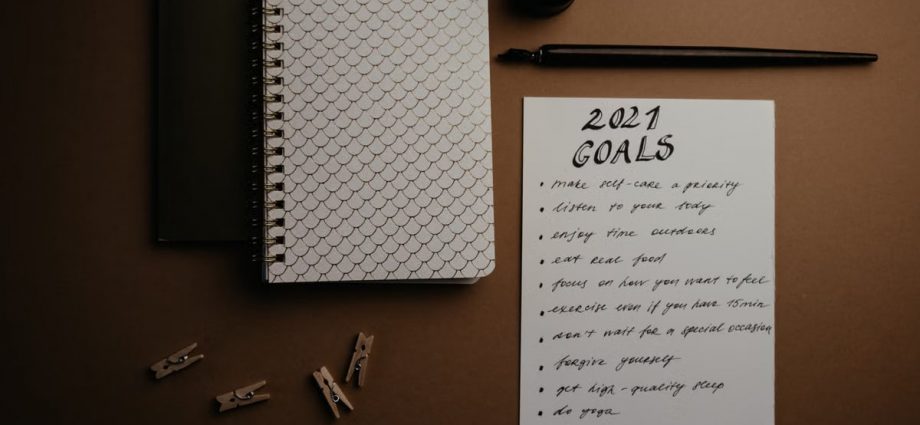 Aesthetic flatlay of notebooks and a 2021 goals list in elegant calligraphy.